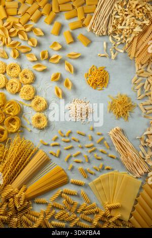 Verschiedene Arten trockener italienischer Pasta, einschließlich Spaghetti, Penne und Fusilli auf hellem Hintergrund Stockfoto