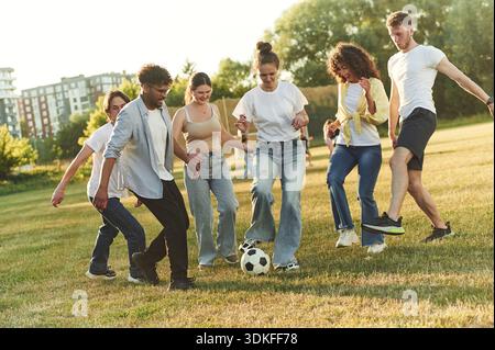 In der legeren Kleidung. Eine Gruppe von Freunden spielt Fußball auf dem Spielfeld. Stockfoto