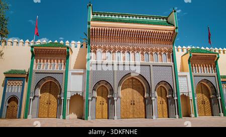 Das monumentale Tor von Fès, das mit zellige Fliesen, geschnitzten Bögen und goldenen Türen dekoriert ist, ist Symbol der traditionellen marokkanischen Architektur unter einem tiefblauen Himmel Stockfoto