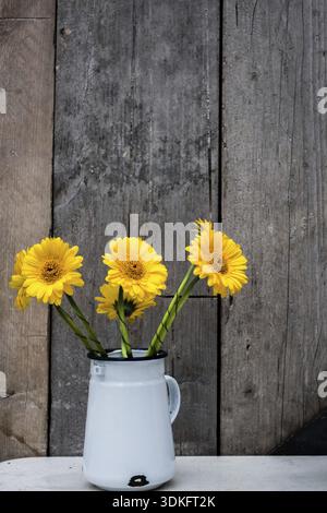Gelbe Gerbera Blumen in einem Metall-Topf auf einen Tisch draußen restaurant Stockfoto