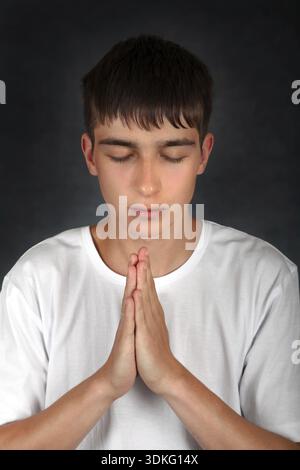 Junger Mann, der auf dem dunklen Hintergrund betet Stockfoto