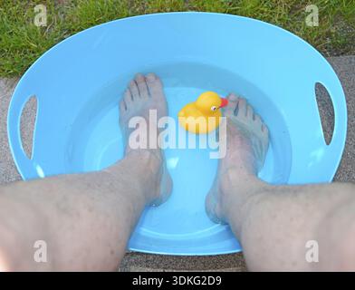 Kühlung, Wärme, Hitzewelle, Kühlung, Füße, Fuß, Wasser, kalt, Abkühlen, Wanne, bunt, blau, gelb, Fußbad, Ente, Plastikente, quietschende Ente, Müll Stockfoto