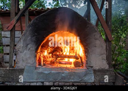 Traditioneller Holzschlammofen im Freien mit brennendem Holz im Inneren in Florestopolis Brasilien Stockfoto