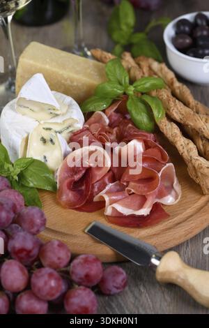Essen, Antipasto. Wein-Set Snacks aus getrocknetem Schinken, Brie Käse mit Schimmel, Parmesan mit grissini, Oliven und rosa Trauben Stockfoto