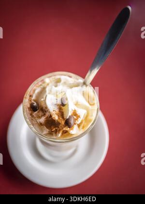 Kaffee Latte im Longdrinkglas mit Sahne, Cinnanmon und Kaffee Bohnen als Beilage Stockfoto