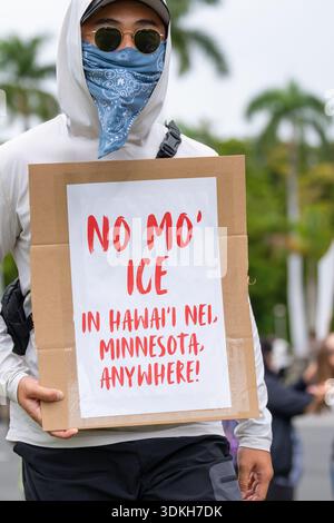 Der maskierte Demonstrant hält ein kühnes „No Mo’ ICE“-Zeichen in Minneapolis oder Hawaii, während sich die Demonstranten gegen EIS erheben, während sich die „No Kings“-Bewegung verstärkt. Stockfoto