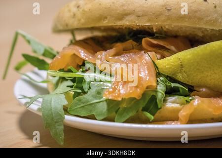 Frühstück Brötchen auf einem Teller, gefüllt mit Räucherlachs und Rucola Stockfoto
