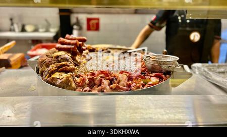 Gemischtes rohes und gekochtes Fleisch auf Tablett in der Restaurantküche, Koch arbeitet im Hintergrund, Lebensmittelzubereitung und Gastronomie-Konzept Stockfoto