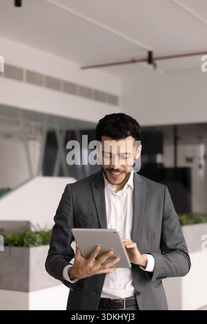 Konzentrierter männlicher Büroangestellter im Anzug, der an einem Tablet arbeitet Stockfoto
