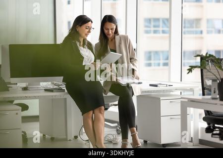 Zwei multinationale Frauen, die an einem Projekt mit Tablet arbeiten Stockfoto