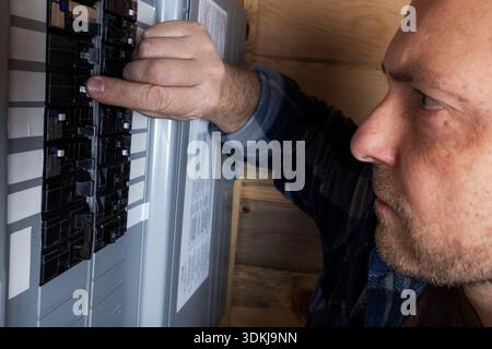 Nahaufnahme eines Hausbesitzers, der die elektrischen Leistungsschalter oder den Sicherungskasten überprüft, um die Stromversorgung wiederherzustellen. Stockfoto