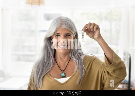 Frau, die Schlüssel aus dem neuen Haus hochhält, Porträt Stockfoto
