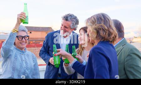 Seniorenfreunde, die auf der Dachterrasse feiern und gemeinsam Bier trinken Stockfoto