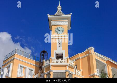 Island Phu Quoc Vietnam 5,7.2025. Ein hohes gelbes Gebäude mit einem Uhrturm und einem Balkon. Der Uhrturm hat eine Uhr und das Gebäude ist surr Stockfoto