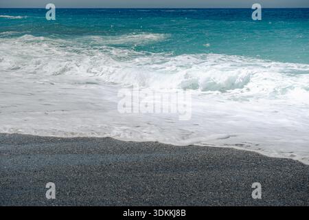 Nahaufnahme von Wellen, die über den Sand an einem Strand an der Küste Kretas schweben Stockfoto