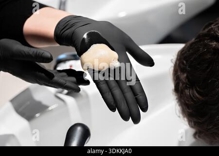 Friseurin, der Shampoo aufwendet und Haare eines Kunden in einem Friseursalon massiert Stockfoto