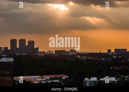Dramatische Sonnenstrahlen durchdringen dunkle Wolken über die Skyline von Kuala Lumpur Stockfoto