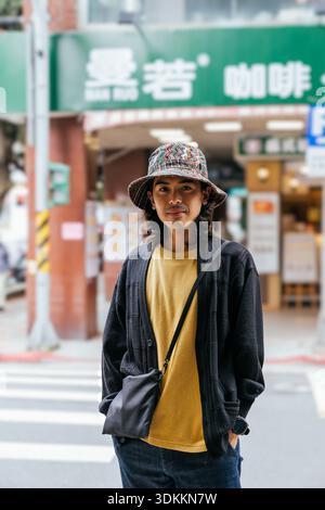 Asiatischer Mann mit Eimerhut, der auf der Stadtstraße steht Stockfoto