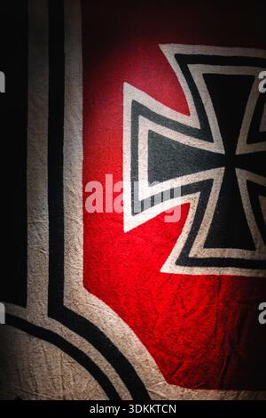 Eine Flagge zeigt das Symbol, das mit dem Nazi-Regime in Verbindung steht, in einem schwach beleuchteten Bereich Stockfoto