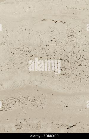 Die Oberfläche des Sandes zeigt verschiedene Formen und Muster. Kleine Felsen und Körner zeigen Details bei natürlichem Licht. Die Einstellung ist trocken, typisch für Sandenvir Stockfoto
