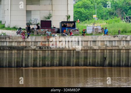 Pekanbaru, Indonesien - 28. September 2025: Menschen, die am Siak River unter der Siak IV Brücke chillen Stockfoto