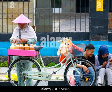 Pekanbaru, Indonesien - 28. September 2025: Ein traditioneller Kräutergetränk-Verkäufer mit ihrem Fahrrad, das während des autofreien Tages auf dem Bürgersteig geparkt wurde Stockfoto