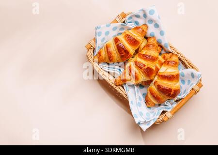 Frisch gebackene Croissants in Korb auf hellem Hintergrund, gemütliches Frühstück Stockfoto