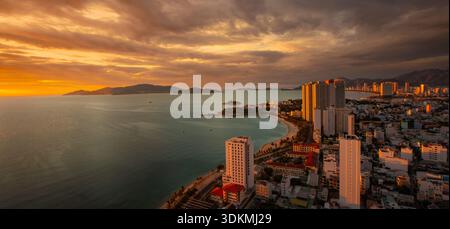 Luftaufnahme der Nha Trang Nordbucht in Vietnam bei Sonnenaufgang mit Meer, Bergen, Himmel und Wohngebäuden. Urbane Küstenlandschaft von oben erfasst, Panorama Stockfoto