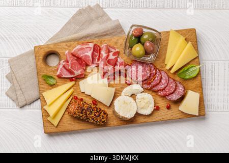 Verschiedene Käse- und Wurstsorten auf einem Holzbrett, klassische Antipasti-Platte für Wein und Zusammenkünfte Stockfoto