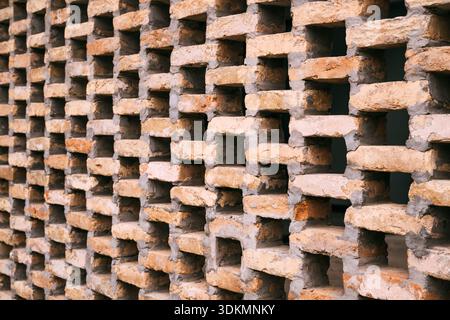 Detaillierte Ansicht der strukturierten Ziegelwand mit sich wiederholenden geometrischen Mustern, architektonischer Hintergrund mit gemauerter Struktur und Baudesign. Stockfoto