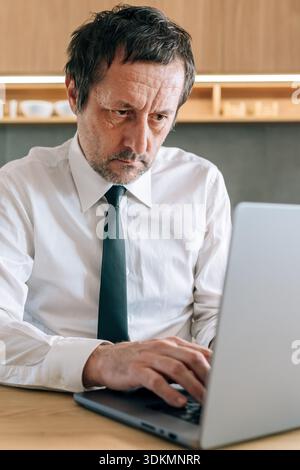 Gestresster Geschäftsmann, der im Home Office mit Laptop arbeitet, selektiver Fokus Stockfoto