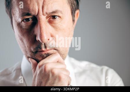 Seriöser Geschäftsmann Hand am Kinn tief in Gedanken Nahaufnahme Porträt, selektiver Fokus Stockfoto