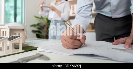Ein Mann schreibt auf ein Blatt Papier vor einer Frau Stockfoto