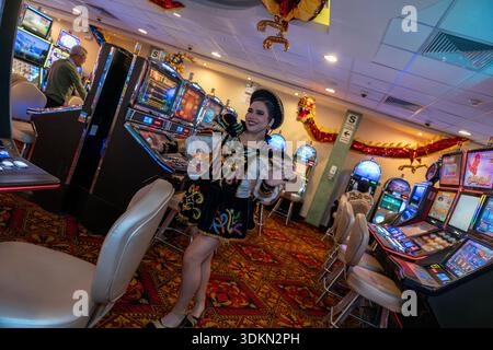 Person in farbenfrohen Volkstrachten in einem Kasino mit beleuchteten Spielautomaten, leuchtenden Lichtern, dekorativen Elementen und gemusterten Teppichen. Stockfoto