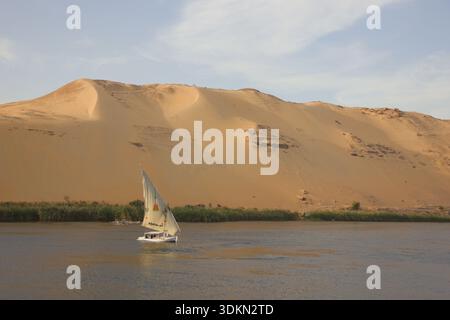 Segelboot auf dem Nil mit goldenen Wüstensanddünen im Hintergrund Stockfoto