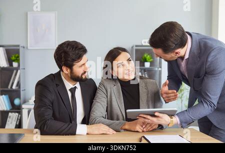 Gruppenporträt glücklicher Geschäftspartner im modernen Büro am Tablet, erfolgreiche Mitarbeiter Stockfoto