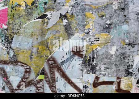 Zerrissene, sprühlackierte Plakate an der Stadtmauer. Urbane Collage Hintergrund Textur. Stockfoto