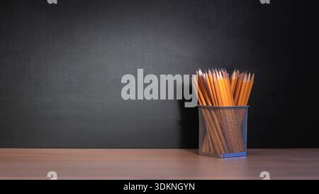 Zurück in die Schule, Korb mit Bleistiften auf dem Schreibtisch vor schwarzer Tafel mit Kopierraum Stockfoto