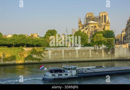 Frankreich. Paris. Sonnigen Sommermorgen auf der Seine Böschung. Notre Dame im Gerüst nach einem Brand im Jahr 2019. Schiff auf dem Fluss Stockfoto