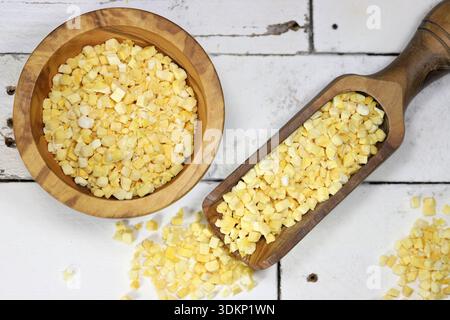 Gefriergetrocknete Mangobaumwürfel in Tafelgeschirr aus Olivenholz auf rustikalem Holzhintergrund Stockfoto