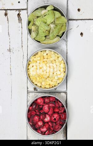Gefriergetrocknete Früchte (Preiselbeeren, Mango, Kiwi) in Aluminiumschalen, die eine Ampel darstellen Stockfoto