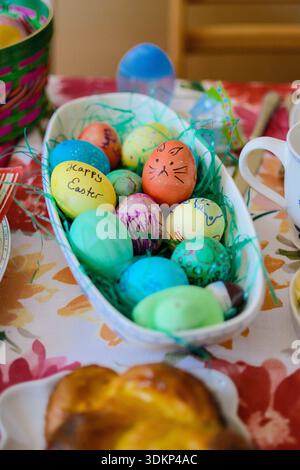 Korb gefüllt mit bunten handgefärbten Ostereiern auf einem festlichen Frühlingstisch. Stockfoto