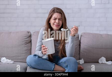 Emotionales Essen. Gestresste Frau weinte auf dem Sofa mit Eimer Eis, sah traurigen Film und Gefühl deprimiert Stockfoto