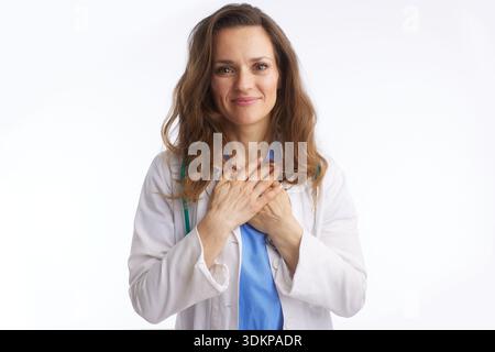 Eine mitfühlende Ärztin in Labormantel und Stethoskop bietet ein sanftes Lächeln mit gefalteten Händen und verkörpert Vertrauen und Sorgfalt. Dieses Porträt reflektiert Stockfoto