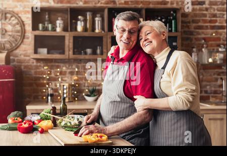 Ältere Frau ihre kochen Mann umarmen in Küche Stockfoto