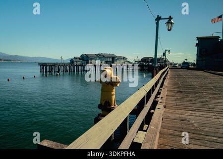 Ruhiger Blick Auf Das Wasser Mit Verankerten Schiffen. Ruhige Hafenlandschaft Mit Booten Und Industriellen Elementen Stockfoto