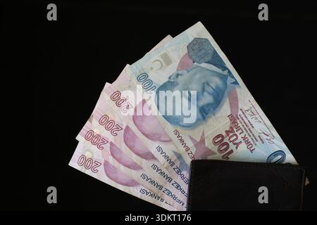 100 türkische Lira-Banknoten in Black Wallet: Nahaufnahme von TRY Currency Fan isoliert auf schwarzem Hintergrund für Finanzen Stockfoto