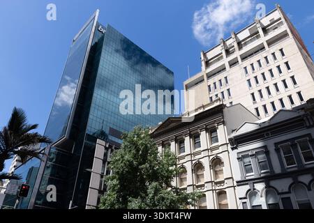 Moderner Glasbüroturm, der sich über historischen Gebäuden in einer Stadtstraße im Zentrum von Auckland erhebt. Stockfoto
