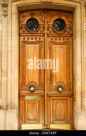 Elegante Holztür mit detaillierten Schnitzereien, schmiedeeisernen Gittern, Messingknöpfen und einem traditionellen Postfach in Paris Stockfoto