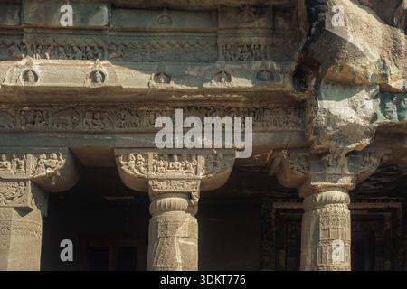 Ajanta, Indien - 26. Dezember 2025: Blick auf alte Steinschnitzereien zieren die Säulen und Türstürze und werfen Schatten, die über die verwitterte Oberfläche tanzen Stockfoto